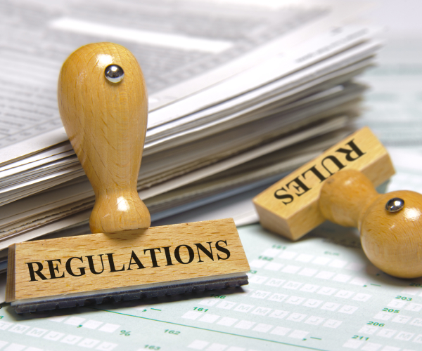 rubber stamps marked with regulations and rules next to a pile of documents