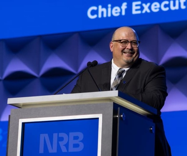 Troy Miller smiles while standing at a podium
