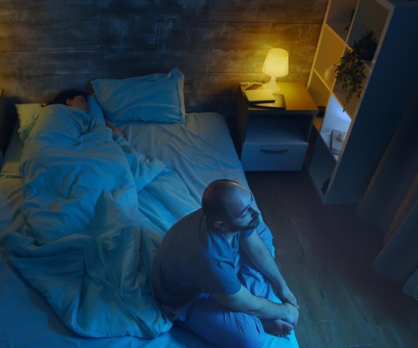 man sitting on bed awake during middle of night