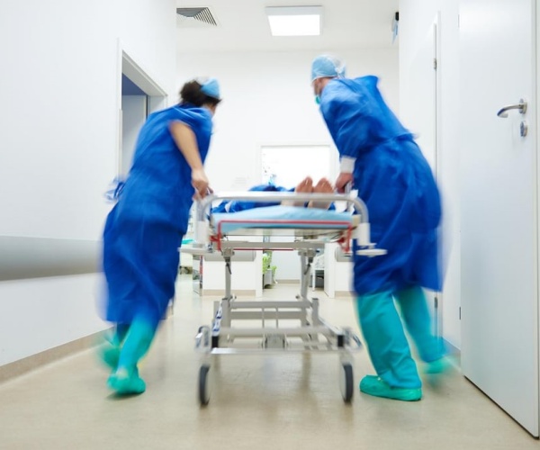 doctors rushing a patient on gurney down hospital hall