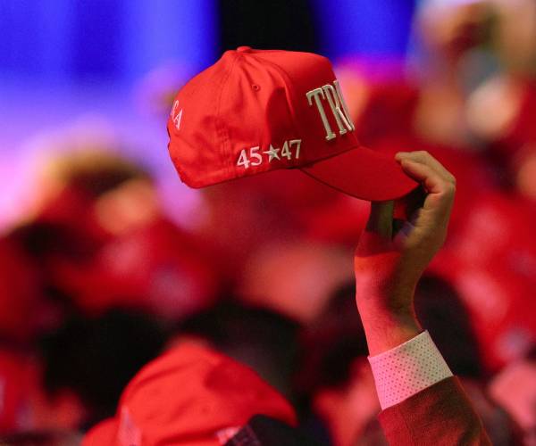 a person holds up a trump hat