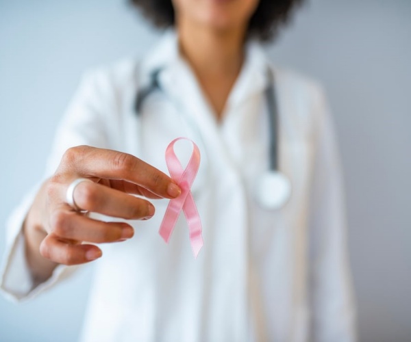 woman holding out pink ribbon for breast cancer awareness