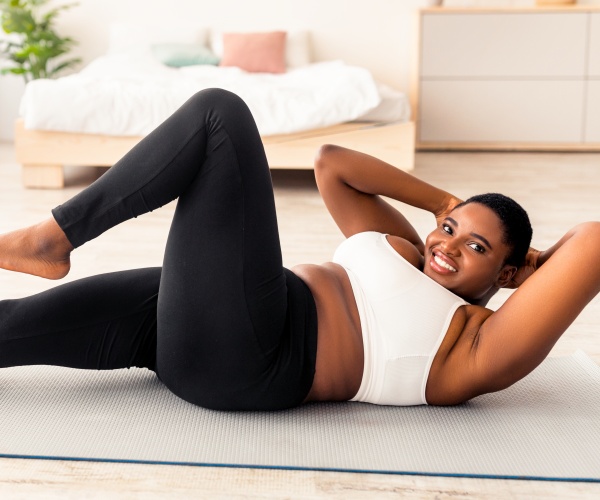 fit, overweight woman on mat doing sit ups