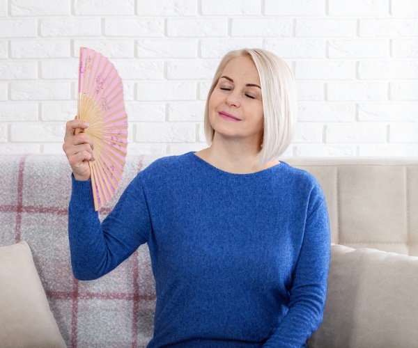 woman with hot flashes fanning herself