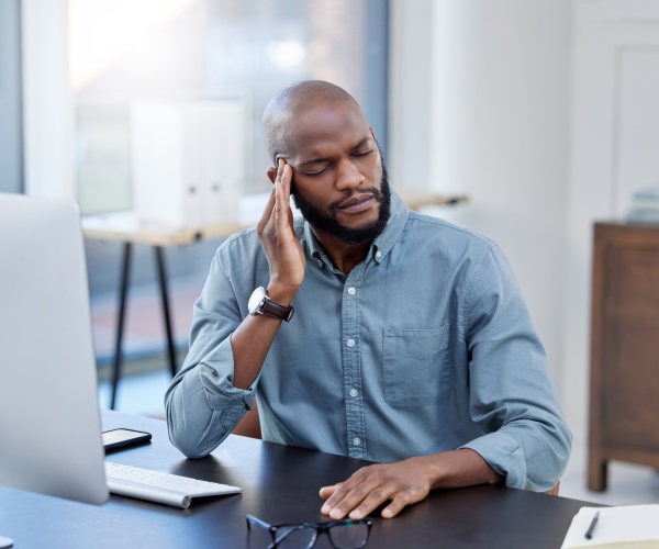 man at working with hand to head due to headache