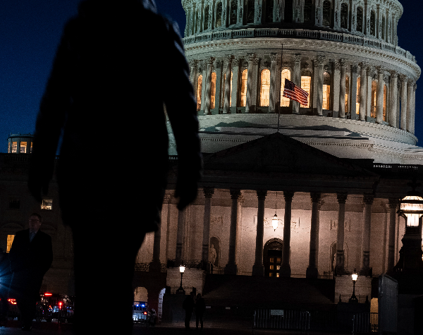 man walking in front of capitol building at night