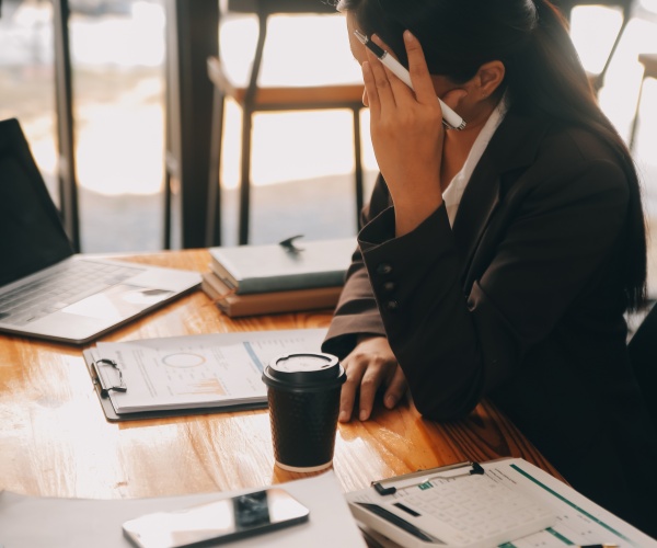 a woman feeling sick at work, holding up head, hiding from co-workers