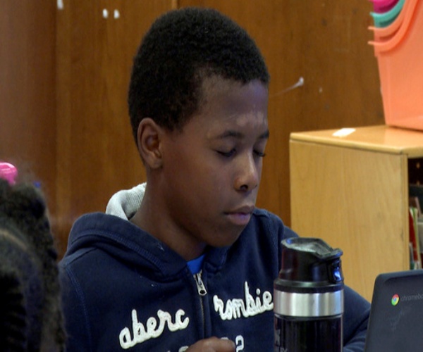 young boy meditating with class in school