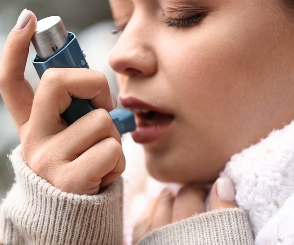 teenaged girl using an inhaler for asthma