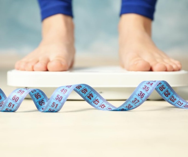 woman's feet on scale, measuring tape