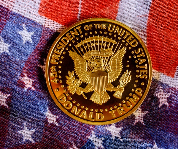 president donald trump gold coin against red, white and blue united states flag background 