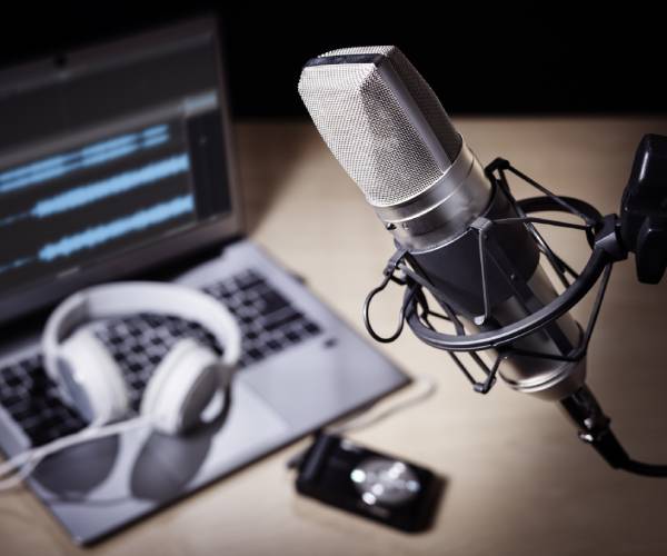 Podcast microphone, laptop computer, camera, headphones on desk