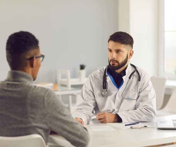 male doctor talking to male patient in his office