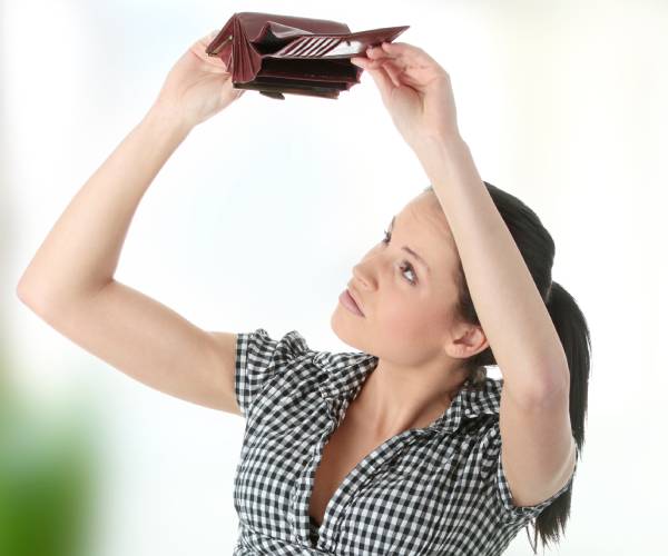 a young woman looking at an empty wallet she is holding above her head