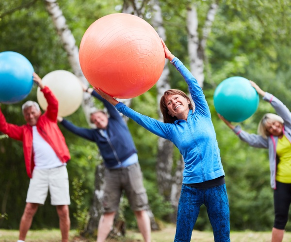 older adults exercising outside with big exercise balls