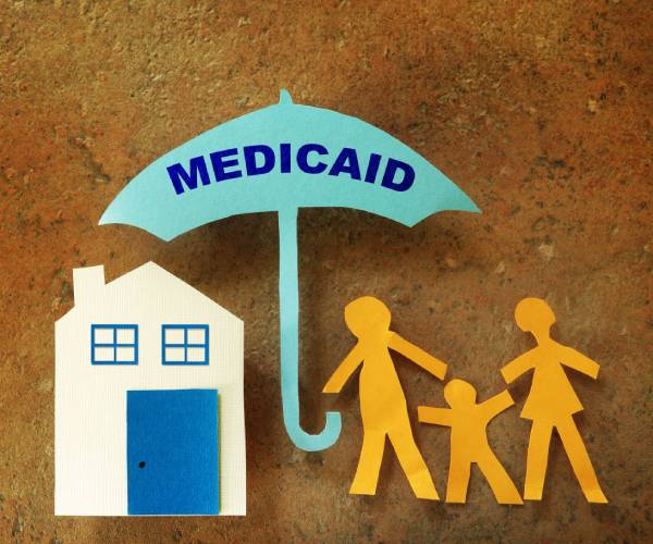 a house and a family under an umbrella labeled medicaid