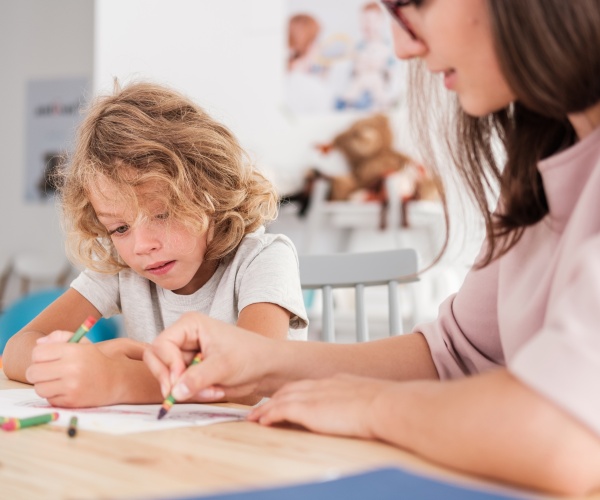 child with autism coloring with therapist