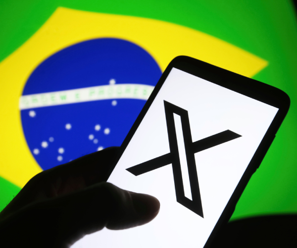 a hald holding a cellphone with X on it in front of a brazilian flag