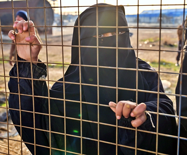 prisoner with hands on fence
