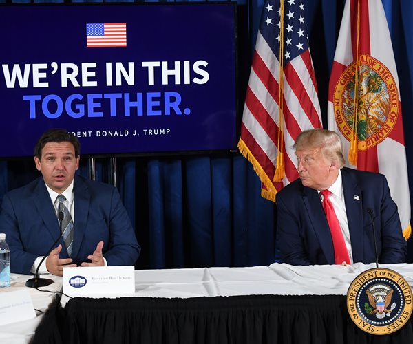 Donald Trump looking to his right at a table with Ron DeSantis 