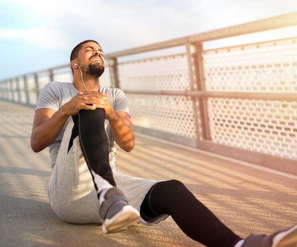 man on ground holding knee due to injury while jogging