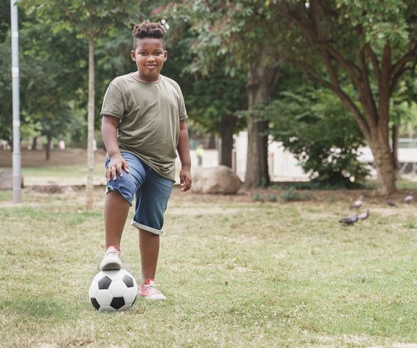 boy standing in field with soccer ball