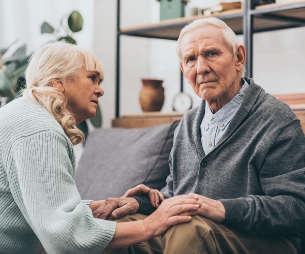 woman comforting man with dementia sitting on couch