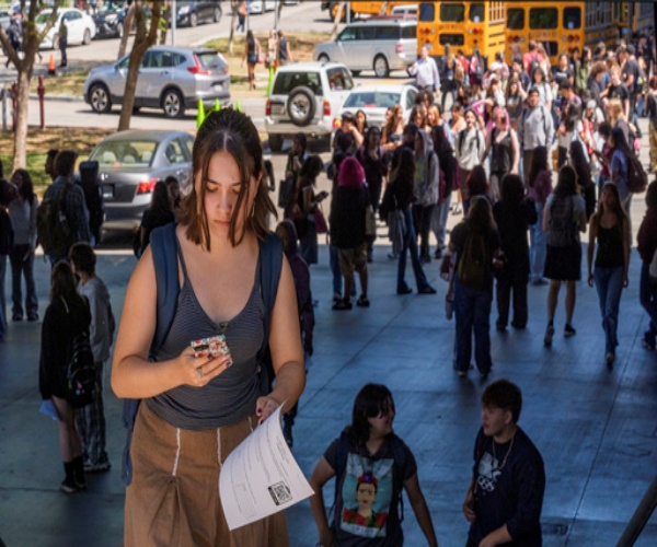 student outside school looking at smartphone