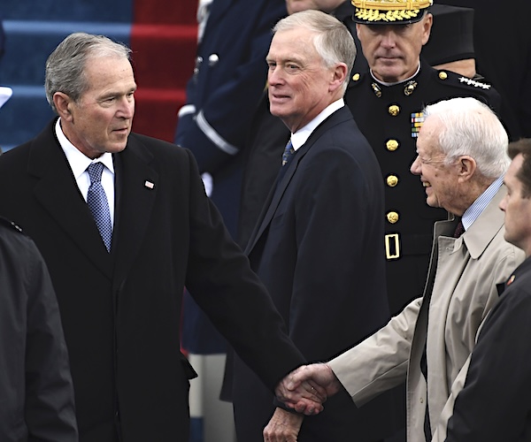 george w. bush grabs the hand of jimmy carter during an inauguration ceremony