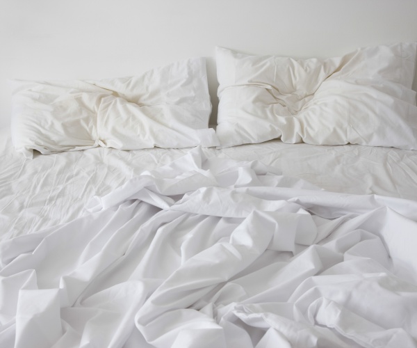 an unmade bed with white sheets