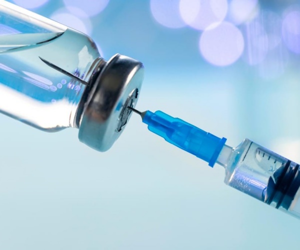 closeup of syringe in vial of vaccine