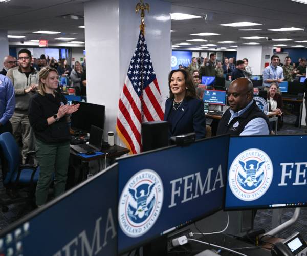 kamala harris behind computer screens with the fema logo on them