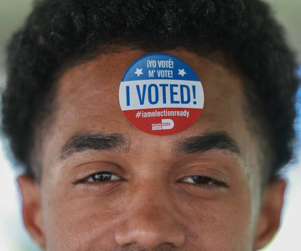 a man with a voter sticker on his forehead