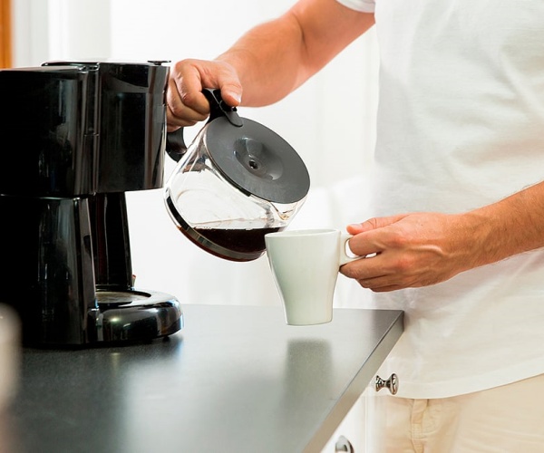 man pouring coffee into cup from coffee pot