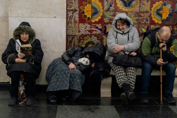 people bundled up in coats and sitting in an underground bunker