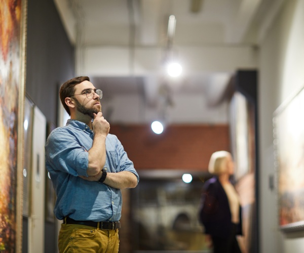 man looking at a painting in a museum