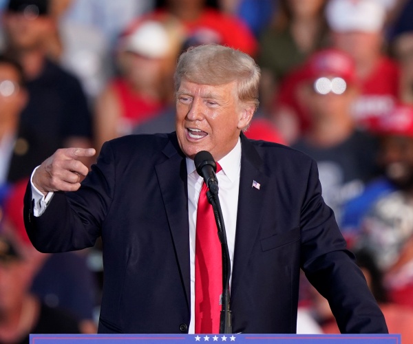 donald trump gestures while speaking into a microphone