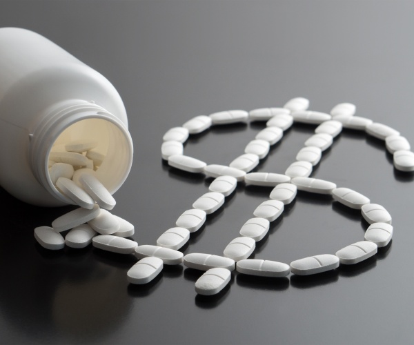 bottle of pills spilling out into shape of dollar sign