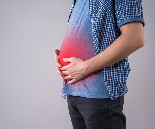 man in blue t-shirt holding belly fat