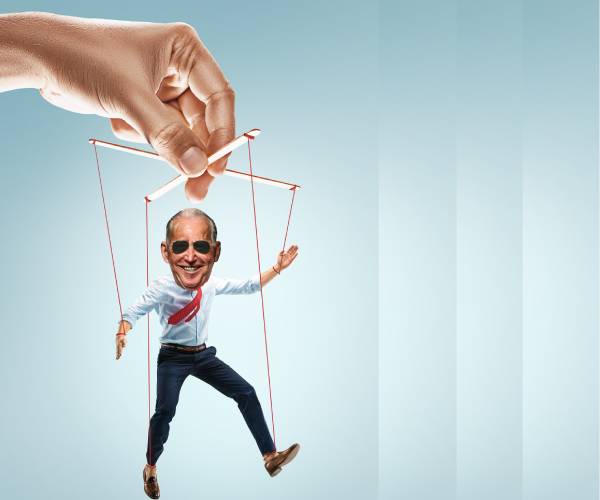 a hand holding puppet strings with a puppet below that has joe biden's face