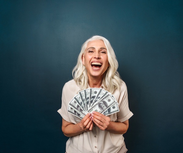 woman smiling holding $100 dollar bills