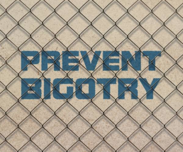 the words prevent bigotry behind a chain link fence