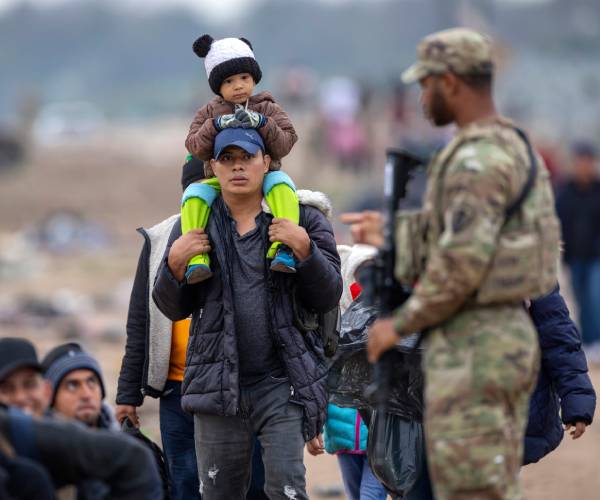 a guard watches over migrants