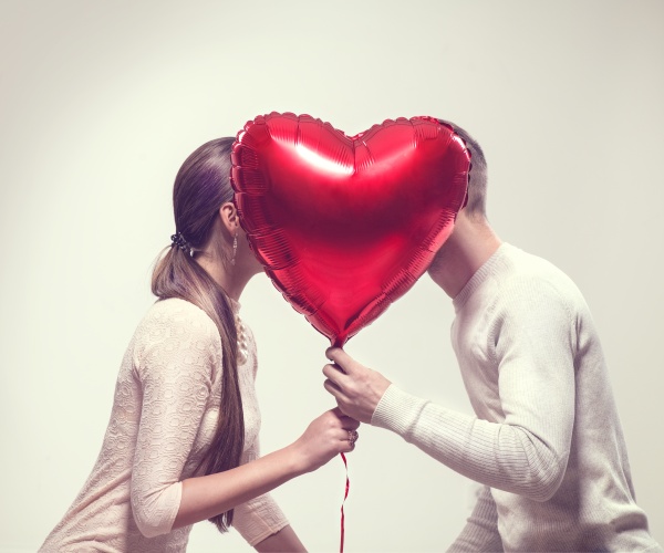 young man and woman behind heart balloon