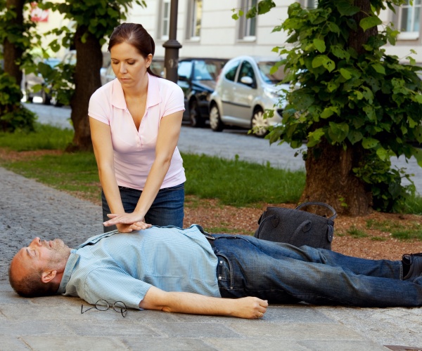 woman performing CPR on man on ground