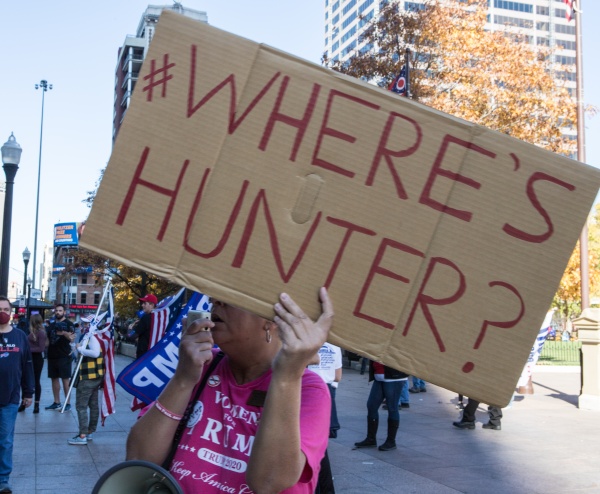 person holding a cardboard sign that reads wheres hunter