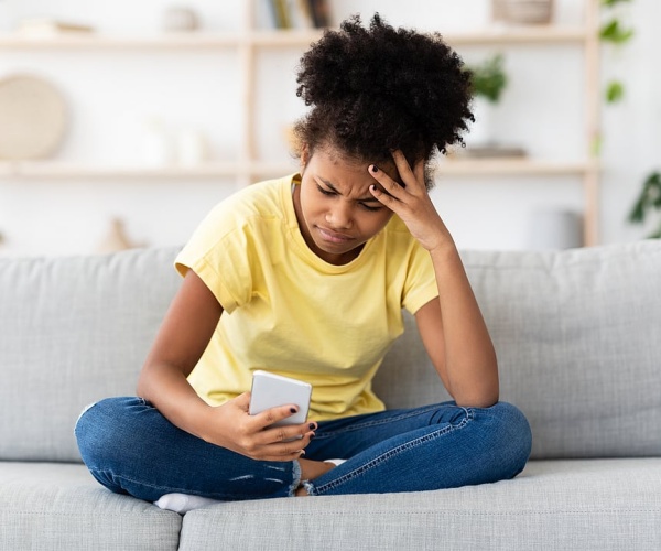 young girl looking anxious while looking at smartphone