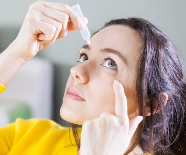 woman putting eye drops in eye