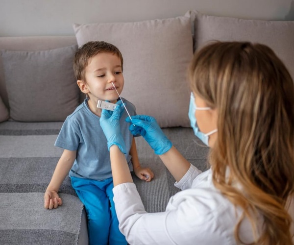 healthcare professional doing a swab test on a young boy