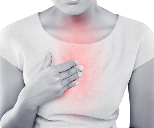 woman holding hand on chest with red highlighting heartburn pain